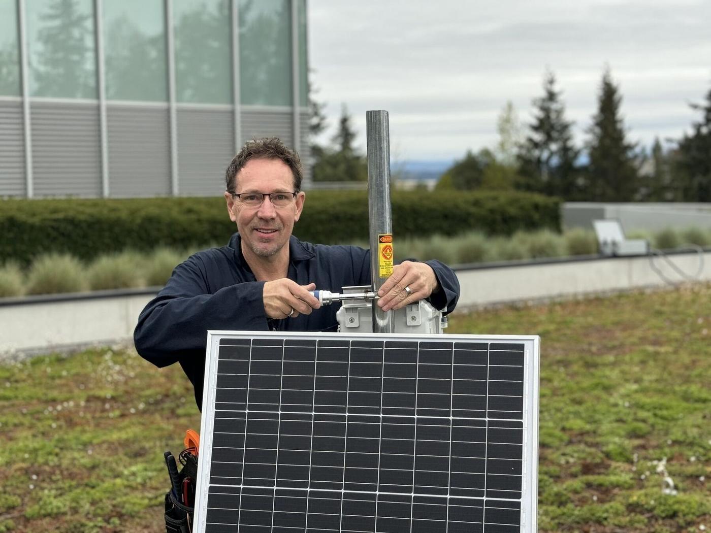 Technician installing a solar-powered LoRaWAN gateway on a green roof