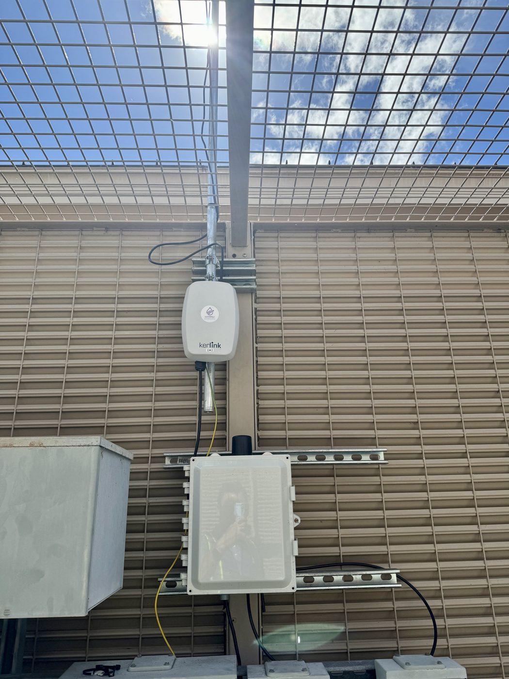 Kerlink LoRaWAN gateway mounted on strut inside a rooftop equipment screen with a power enclosure below