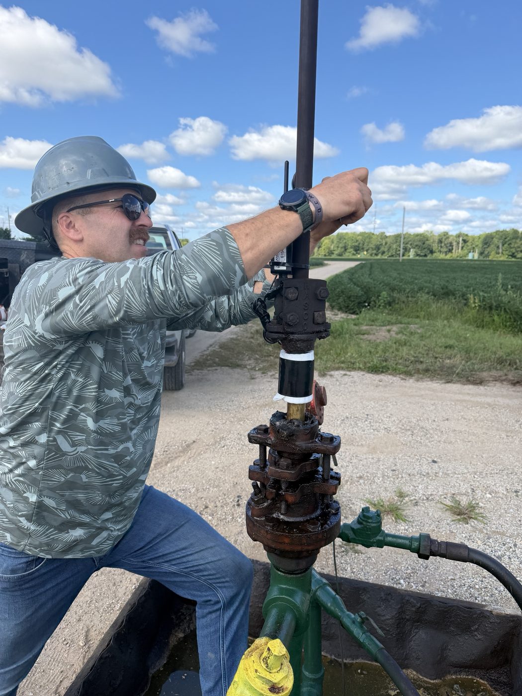 Technician installing a wireless LoRaWAN sensor at a pumpjack wellhead