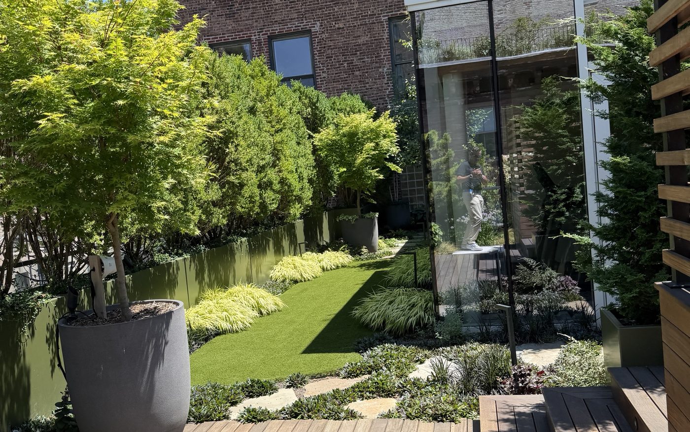 Rooftop terrace garden with a wood deck, containerized trees, lawn and a glass pavilion