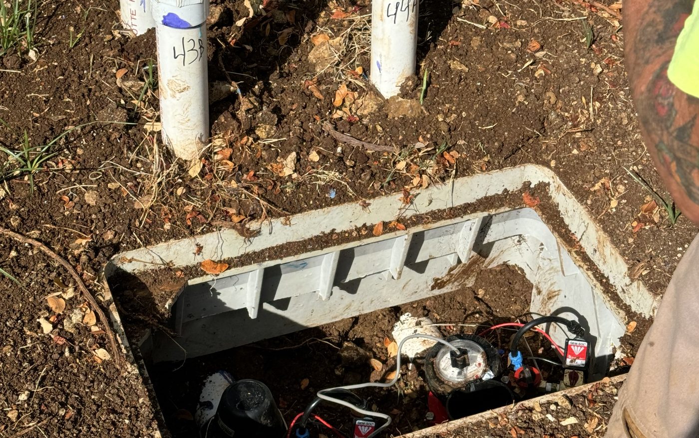 Open irrigation valve box with solenoid valves wired to a wireless controller, quick-coupler risers labeled above