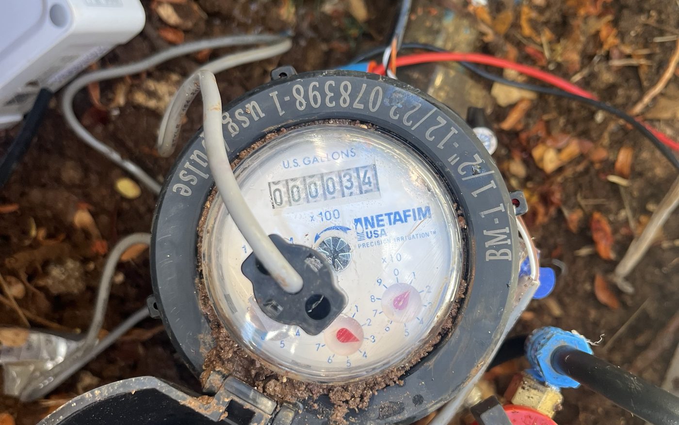Close-up of a water meter register with a pulse-output cable connected in a valve box
